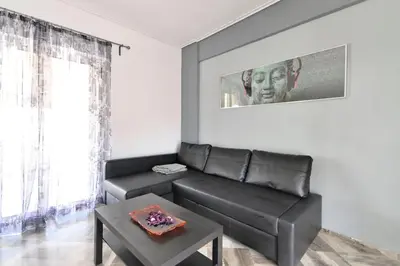 a living room with a black leather couch and a table at 2 level apartment with terrace and Acropolis view in Athens