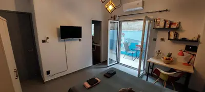 a living room with a television and a room with a table at HoneyBee 3 - Cozy studio in the center of Athens in Athens