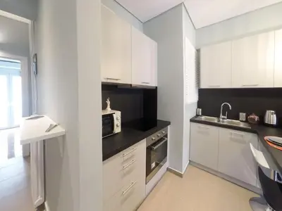 a white kitchen with white cabinets and a microwave at Cozy apartment close to Acropolis in Athens