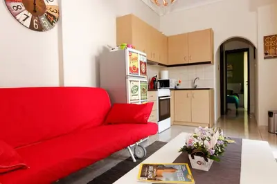 a living room with a red couch and a kitchen at Big terrace near metro and Athens center in Athens