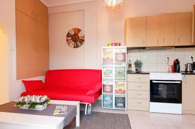 a living room with a red couch and a kitchen at Big terrace near metro and Athens center in Athens