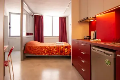 a bedroom with a bed with red curtains and a kitchen at Red cosy studio in Athens center in Athens