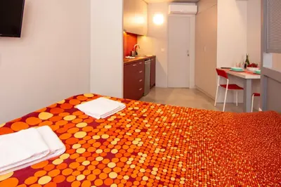 a room with a bed with an orange and white bedspread at Red cosy studio in Athens center in Athens