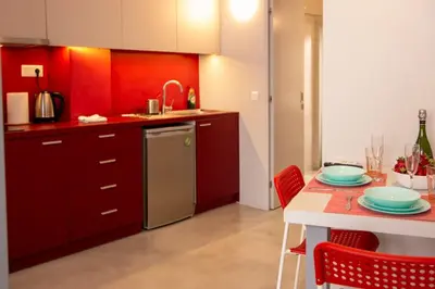 a kitchen with red cabinets and a table with plates on it at Red cosy studio in Athens center in Athens