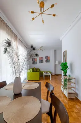 a living room with a table and chairs and a green couch at Penthouse 2Bd apartment in the heart of Koukaki in Athens