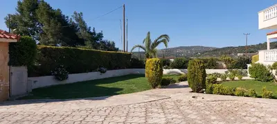 a garden with hedges and a stone walk way at Evelina's studio in Artemida