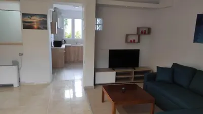 a living room with a blue couch and a television at Evelina's studio in Artemida