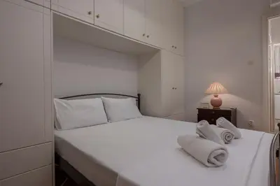 a white bedroom with a large bed with towels on it at ΔΙΠΛΑ ΣΕ ΜΕΤΡΟ , ΚΟΝΤΑ ΣΤΗΝ ΑΚΡΟΠΟΛΗ in Athens