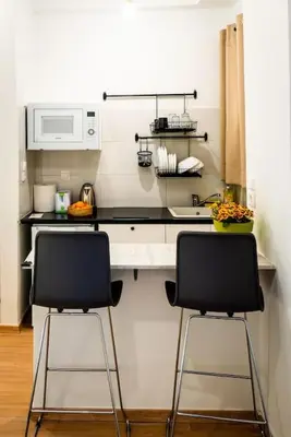 a kitchen with two chairs in front of a counter at Acropolis Explorer Studio by WeHost Athens in Athens