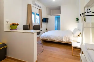 a bedroom with a bed and a desk with chairs at Acropolis Explorer Studio by WeHost Athens in Athens