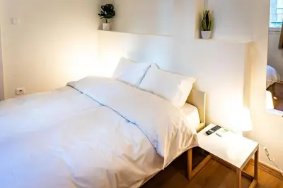 a bedroom with a white bed and a night stand at Acropolis Explorer Studio by WeHost Athens in Athens