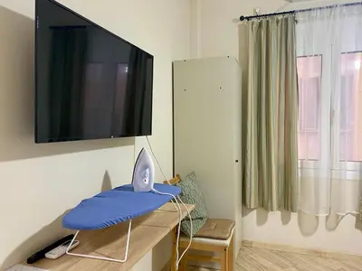 a room with a tv and a desk with a blue pillow at A modern flat in the centre in Athens
