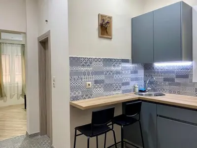 a kitchen with blue tiled walls and a counter with stools at A modern flat in the centre in Athens