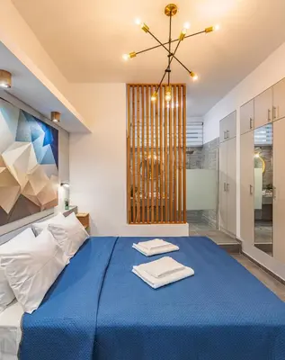 a bedroom with a blue bed and a chandelier at Theo's Cozy Apartment's near Athens airport in Spáta