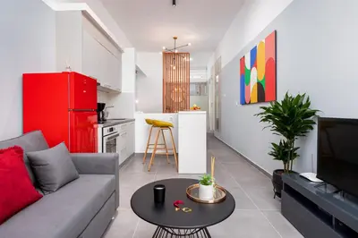 a living room with a couch and a kitchen with a red refrigerator at Theo's Cozy Apartment's near Athens airport in Spáta