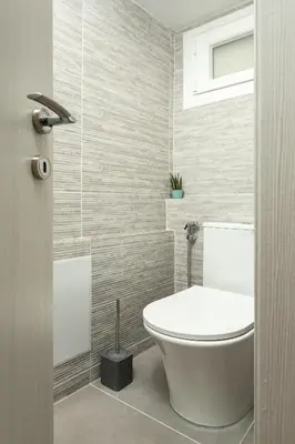 a bathroom with a white toilet and a window at Theo's Cozy Apartment's near Athens airport in Spáta