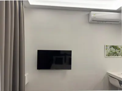 a flat screen tv hanging on a white wall at TiP - ToP Suites in Athens