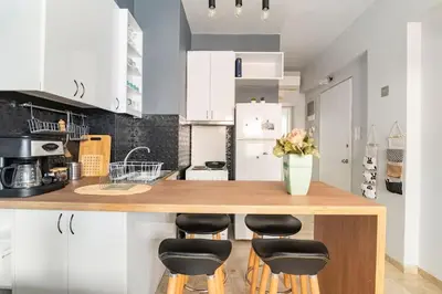 a kitchen with white cabinets and a wooden counter with stools at Sunny apartment right under Parthenon in Athens
