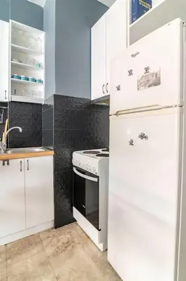 a kitchen with white cabinets and a white refrigerator at Sunny apartment right under Parthenon in Athens