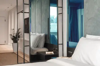 a bedroom with a mirror with a bed and a chair at Dion Luxury Suites in Athens