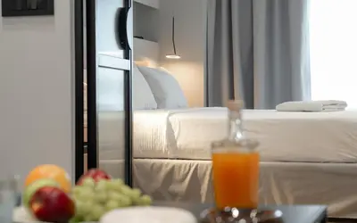 a hotel room with a bed and a glass of orange juice at Dion Luxury Suites in Athens
