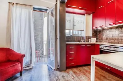 a kitchen with red cabinets and a red chair at Beautiful and cozy studio next to Athens center in Athens
