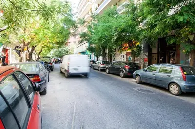 a van driving down a street with parked cars at Beautiful and cozy studio next to Athens center in Athens