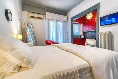a bedroom with a large white bed and a kitchen at Beautiful and cozy studio next to Athens center in Athens