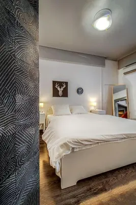 a bedroom with a white bed and a wall at Beautiful and cozy studio next to Athens center in Athens