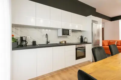 a kitchen with white cabinets and a wooden table at Acropolis Exclusive Apartment in Athens