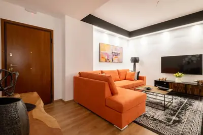 a living room with an orange couch and a flat screen tv at Acropolis Exclusive Apartment in Athens