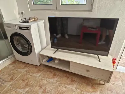 a flat screen tv sitting on a stand next to a washing machine at Quiet Studio with Athens View in Athens