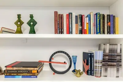 a shelf with books and a clock and books at A newly fully renovated studio in Athens