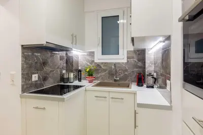 a white kitchen with white cabinets and a sink at A newly fully renovated studio in Athens