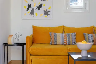 a yellow couch in a living room with a table at Your 4 bdrm Dream House Acropolis View & Jacuzzi in Athens