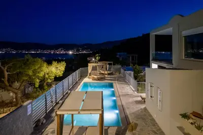 a villa with a swimming pool at night at Be Home Sea View in Porto Rafti
