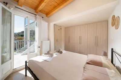a bedroom with a white bed and a large window at Be Home Sea View in Porto Rafti