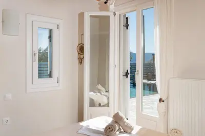 a white bedroom with a door open to a balcony at Be Home Sea View in Porto Rafti