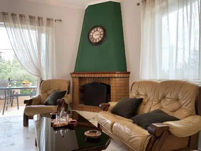 a living room with couches and a fireplace with a clock at Vintage Manor in Anavissos