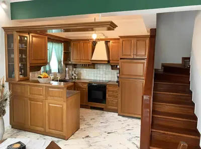 a kitchen with wooden cabinets and a staircase at Vintage Manor in Anavissos