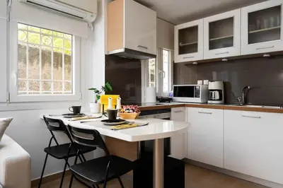 a kitchen with white cabinets and a table and chairs at Modern Two Level Apartment in the Heart of Athens in Athens
