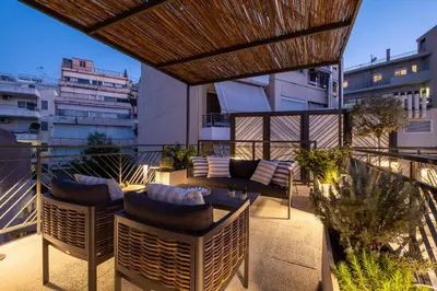 a patio with chairs and a couch on a balcony at Athenian Island Project in Athens