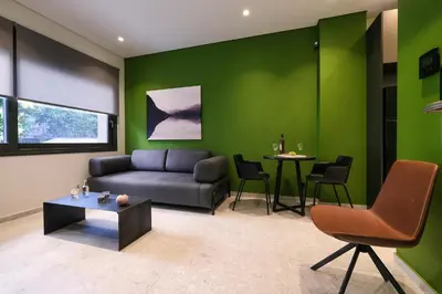 a living room with green walls and a couch and a table at Athenian Island Project in Athens