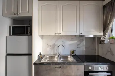 a white kitchen with a sink and a refrigerator at Blue Ark Wanderlust in Athens