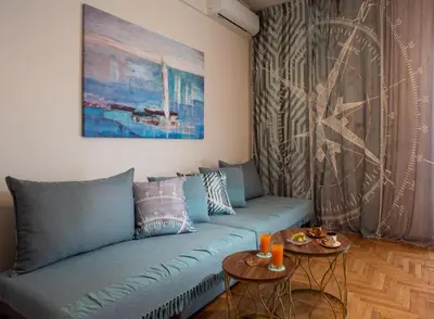 a living room with a blue couch and two tables at Blue Ark Wanderlust in Athens
