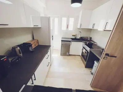 a kitchen with white cabinets and a black counter top at Minimal 3BR Apartment in Athens in Athens