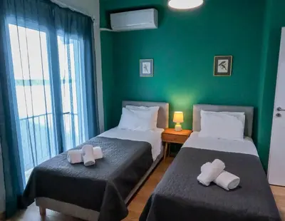 two beds in a room with a green wall at Comfortable apt, next to Archeological museum! in Athens