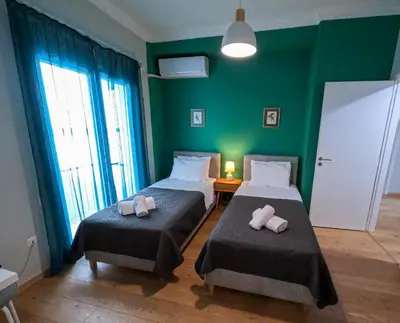 a room with two beds and a green wall at Comfortable apt, next to Archeological museum! in Athens