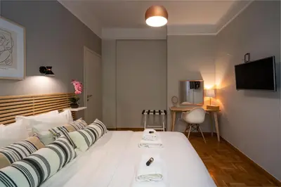 a bedroom with a large white bed with a television on the wall at Athens City Apartment the Nest of Filoxenia in Athens