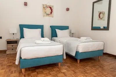 two beds in a room with blue chairs at Esperidon Luxury Apartment Glyfada in Athens